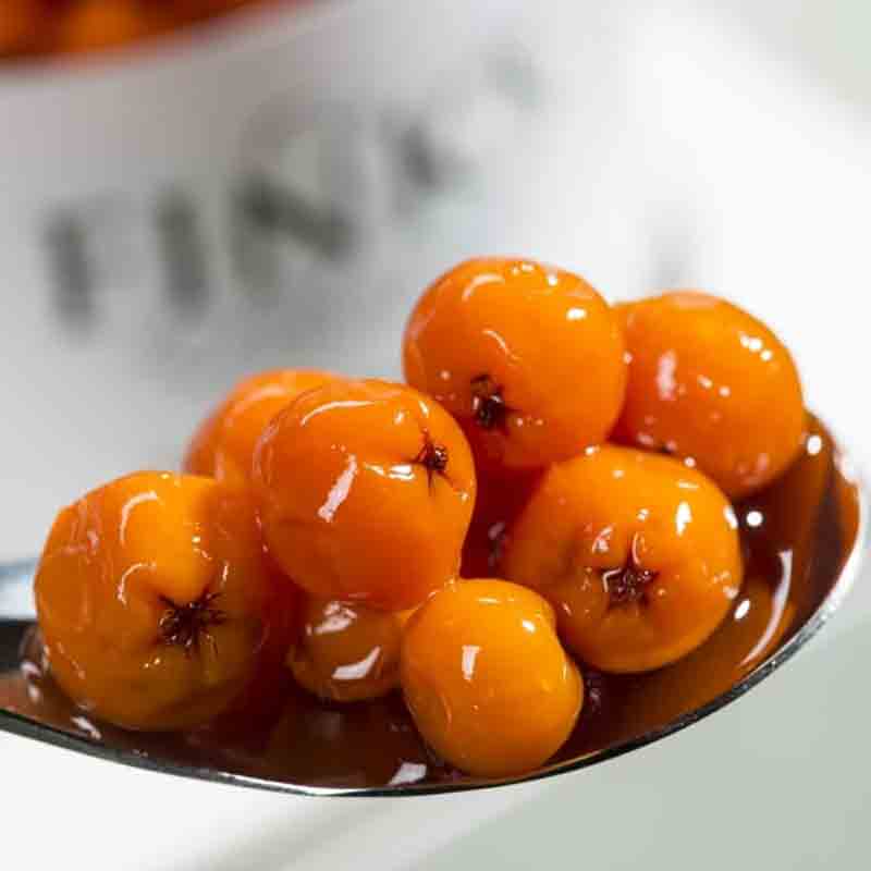 Feinkostbeeren auf Löffel vor Fink-Behälter.