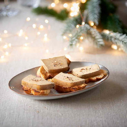 Feinkostplatte mit Foie Gras auf Baguettescheiben, festliche Dekoration.