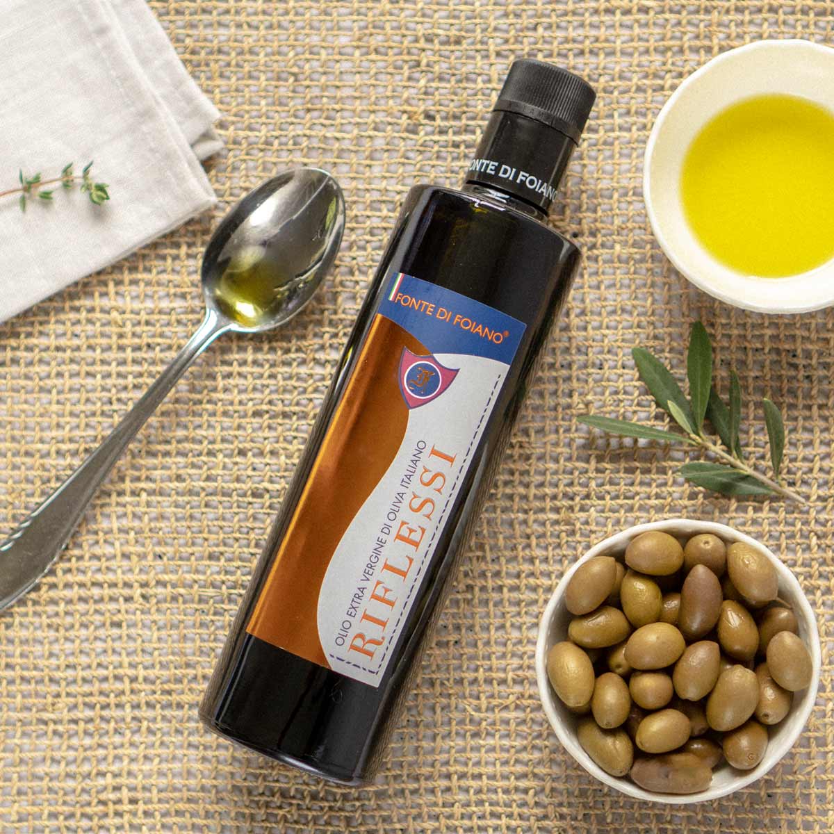 Fonte di Foiano Olivenöl mit Oliven und Löffel.