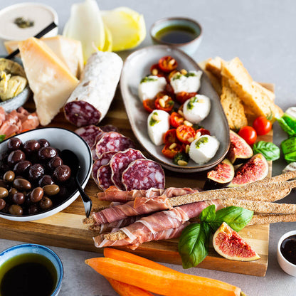 Verschiedene Delikatessen auf Holzbrett mit Oliven, Käse, Wurst.