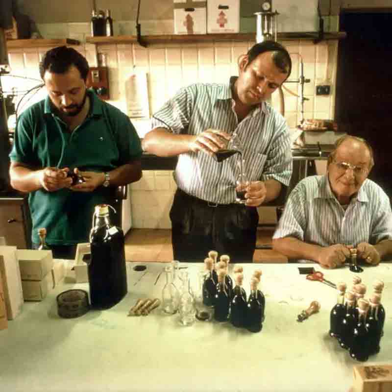 Männer füllen Flaschen mit Essig in einer Küche ab.