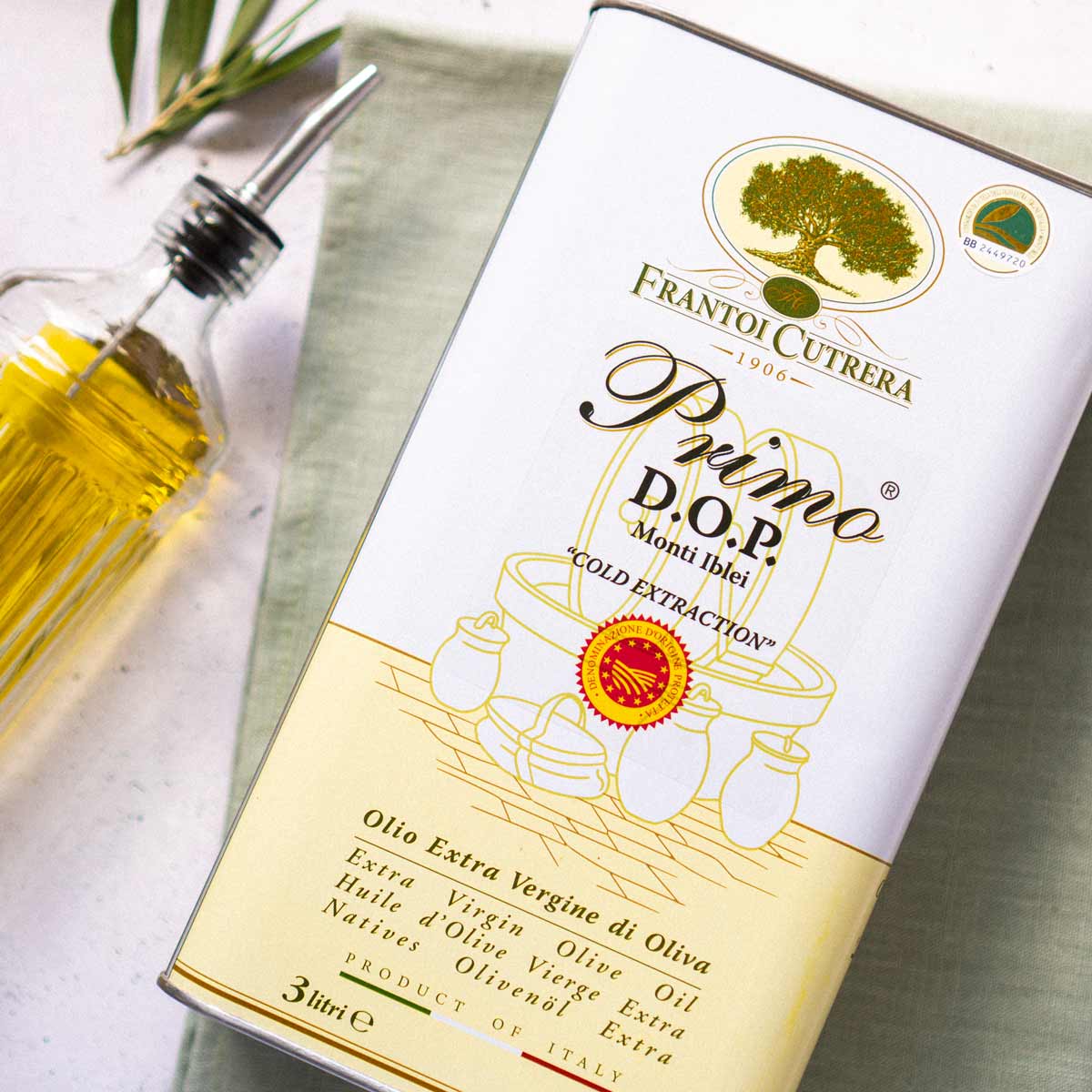 Frantoi Cutrera Olivenöl Kanister auf Tisch mit Flasche.