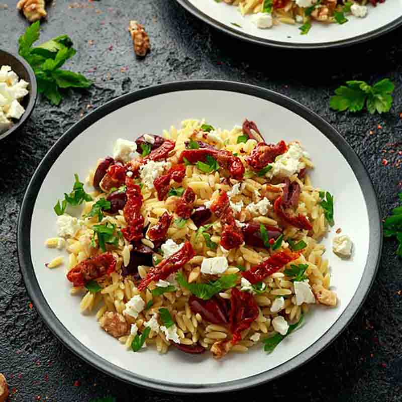 Orzo-Salat mit getrockneten Tomaten, Feta, Walnüssen, Petersilie.