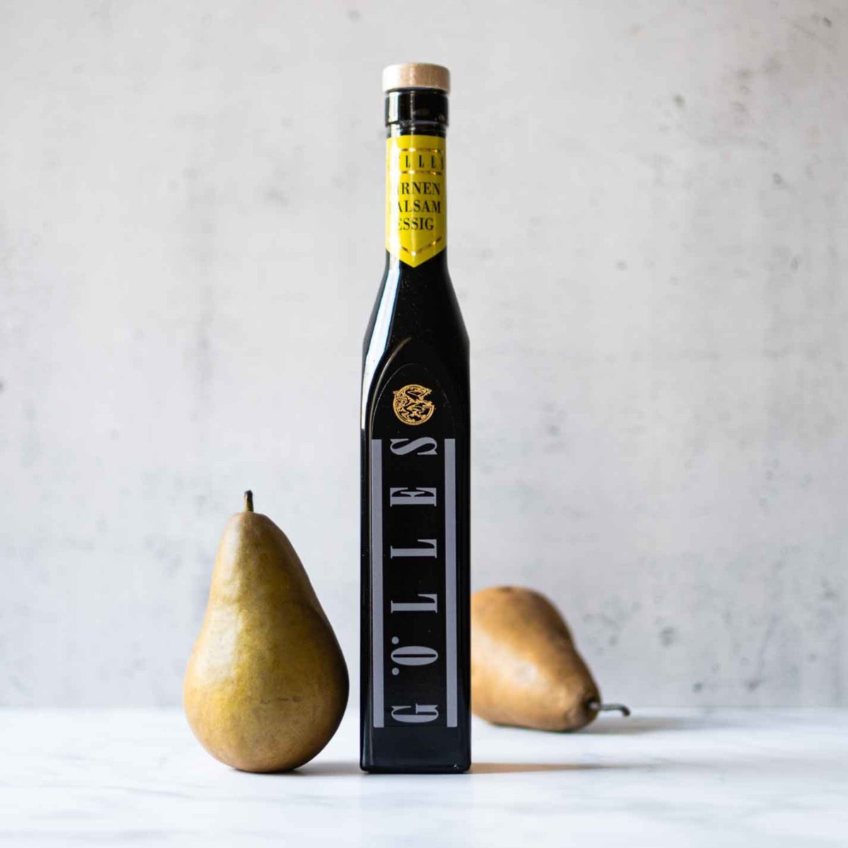Gölles Birnenbalsam Essigflasche mit zwei Birnen daneben.