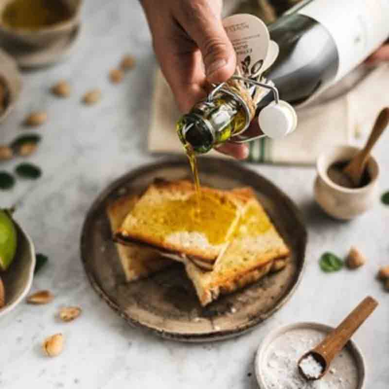 Hand gießt Gradassi Olivenöl auf Brot auf Teller.