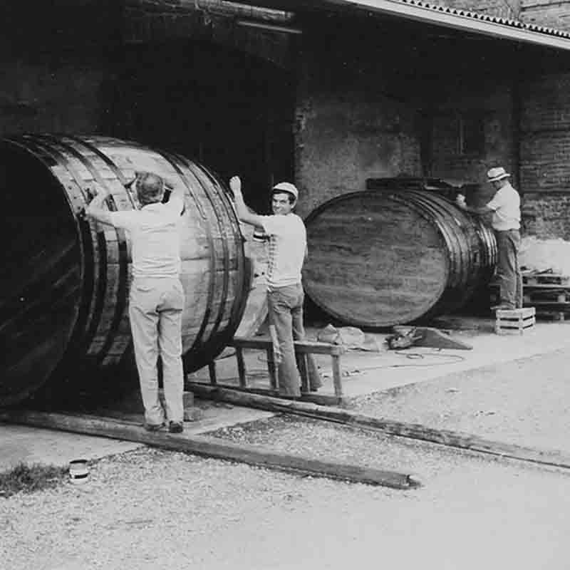 Männer arbeiten an großen Fässern.