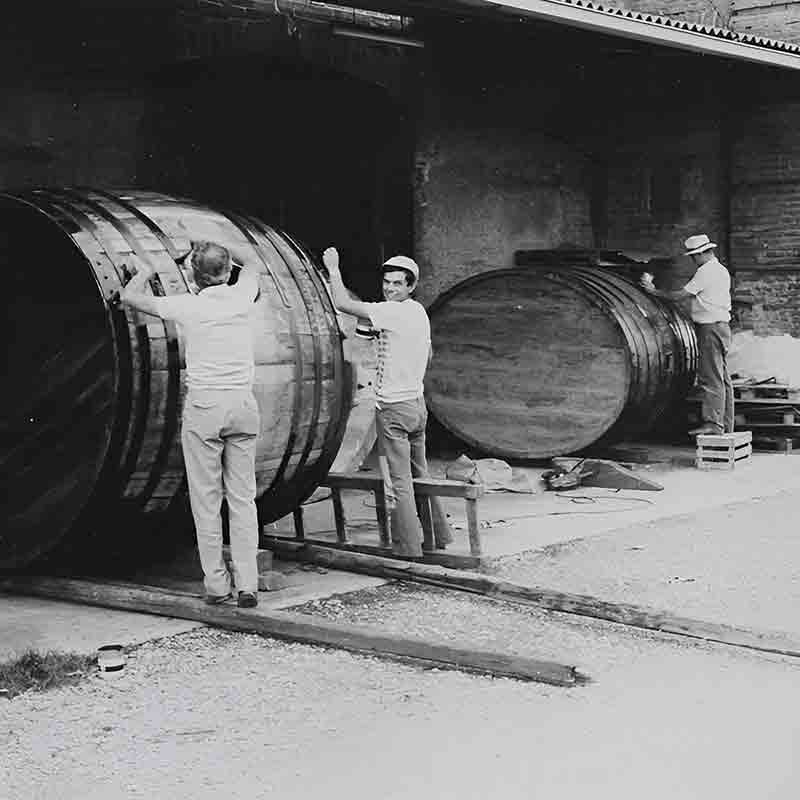 Männer arbeiten an großen Fässern.