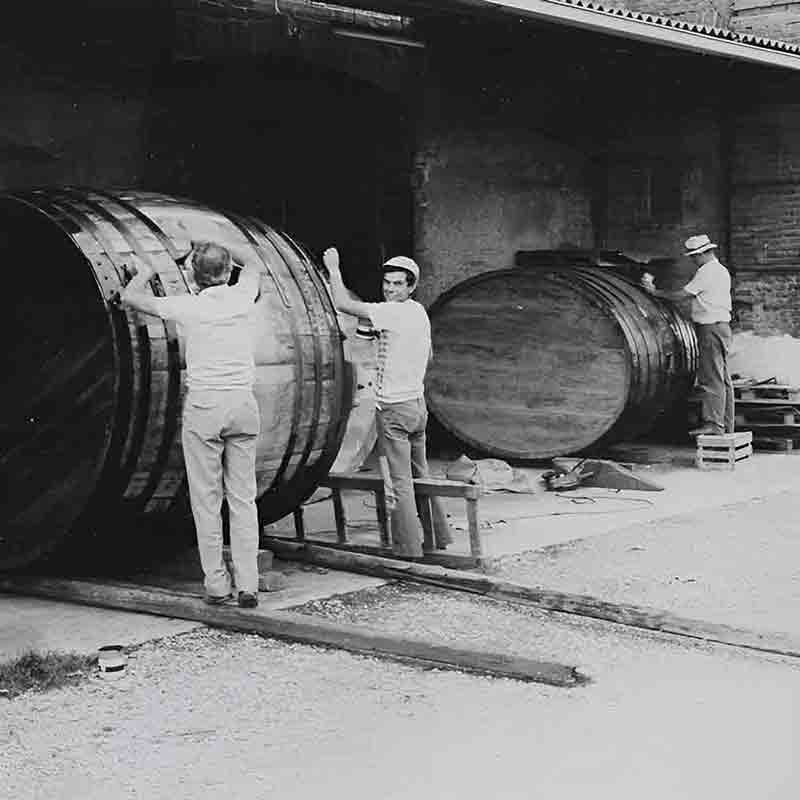 Männer arbeiten an großen Fässern.