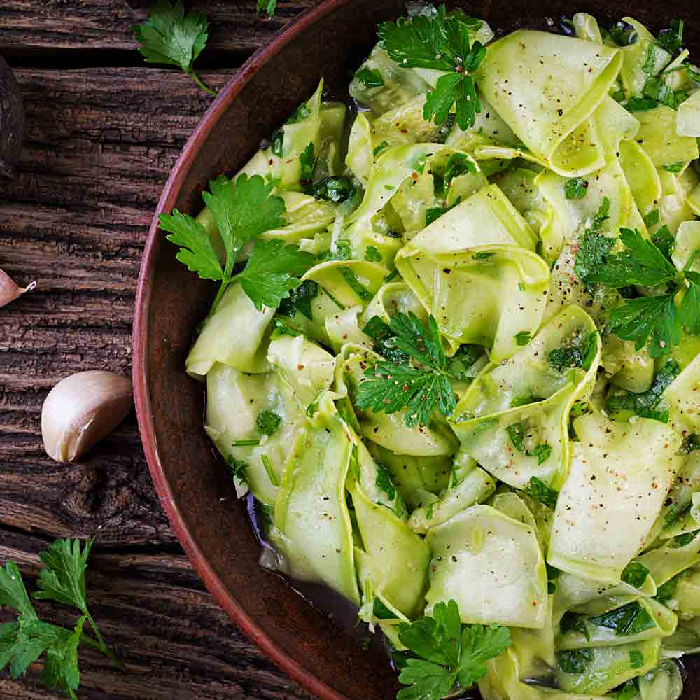 Gurkensalat mit Apfelessig und Rapsöl auf Holztisch.