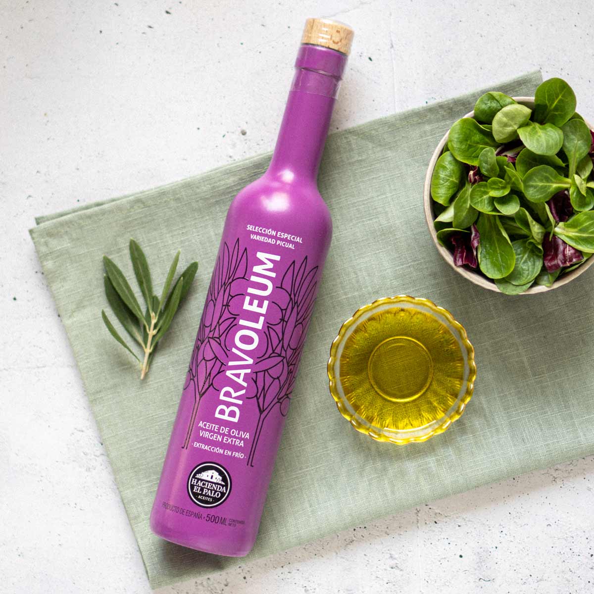 Bravoleum Olivenölflasche, Schale mit Öl, Salatblätter, Olivenzweig.