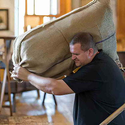 Mann in der Ölmühle Hartlieb mit schwerem Sack auf den Schultern.