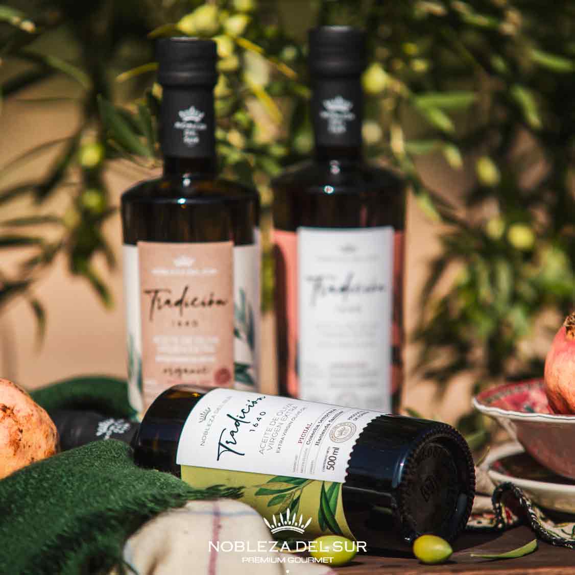 Olivenölflaschen von Nobleza del Sur mit Olivenhintergrund.