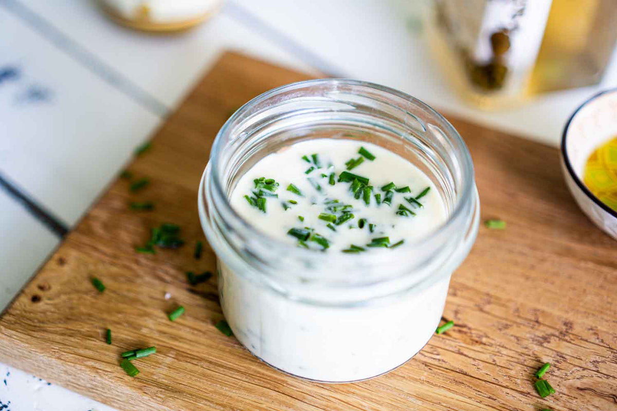 Blick von oben in das Joghurt-Dressing. Frisch geschnittener Schnittlauch ist im Dressing zu sehen.