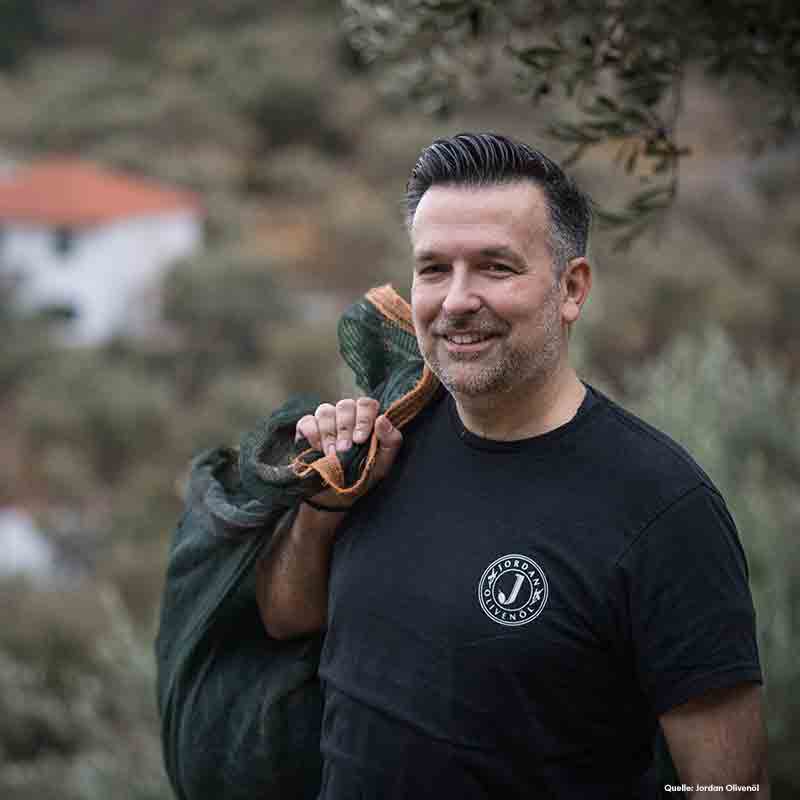 Mann mit Olivenernte im Hintergrund.