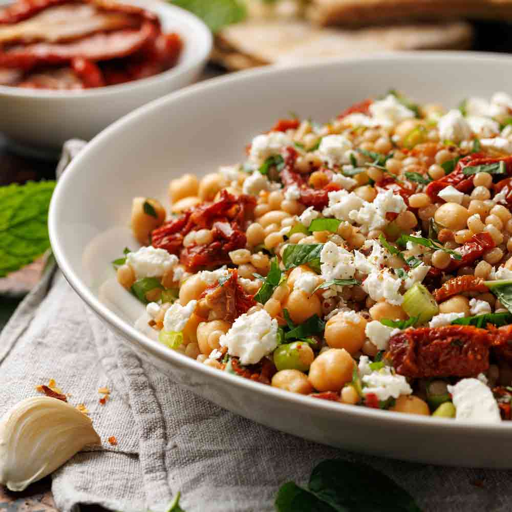 Kichererbsensalat mit getrockneten Tomaten und Feta in Schüssel.