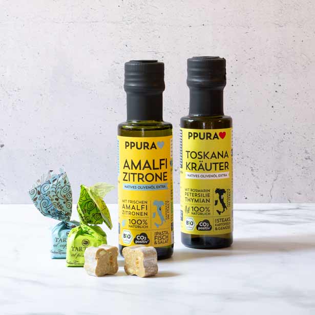 Olivenölflaschen und Pralinen von PPURA auf hellem Hintergrund.