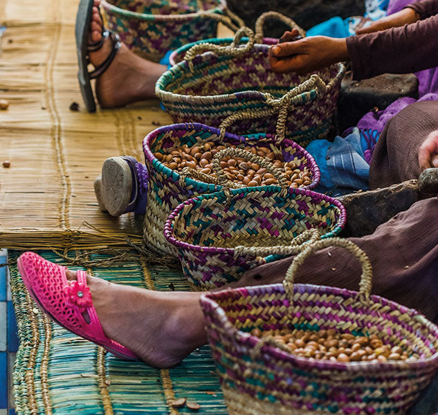 Menschen knacken Nüsse in geflochtenen Körben auf Boden.