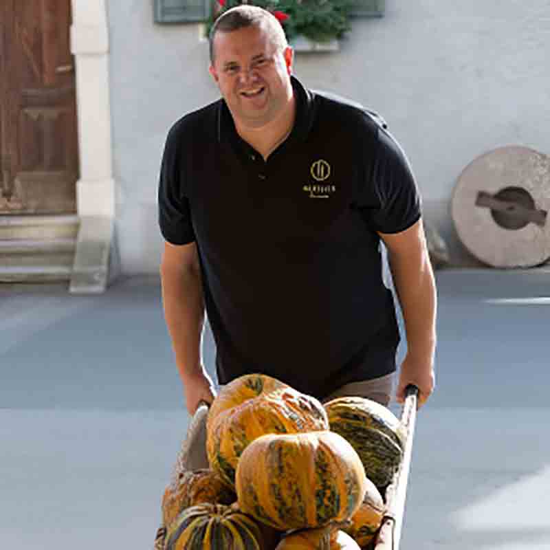 Mitarbeiter der Ölmühle Hartlieb hat Kürbisse in der Schubkarre.