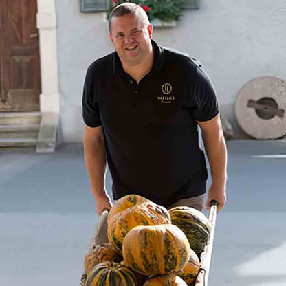 Mitarbeiter der Ölmühle Hartlieb hat Kürbisse in der Schubkarre.