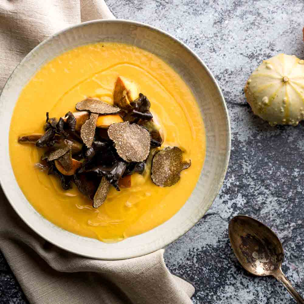 Kürbissuppe mit Trüffeln, dekoriert auf einem Tisch.