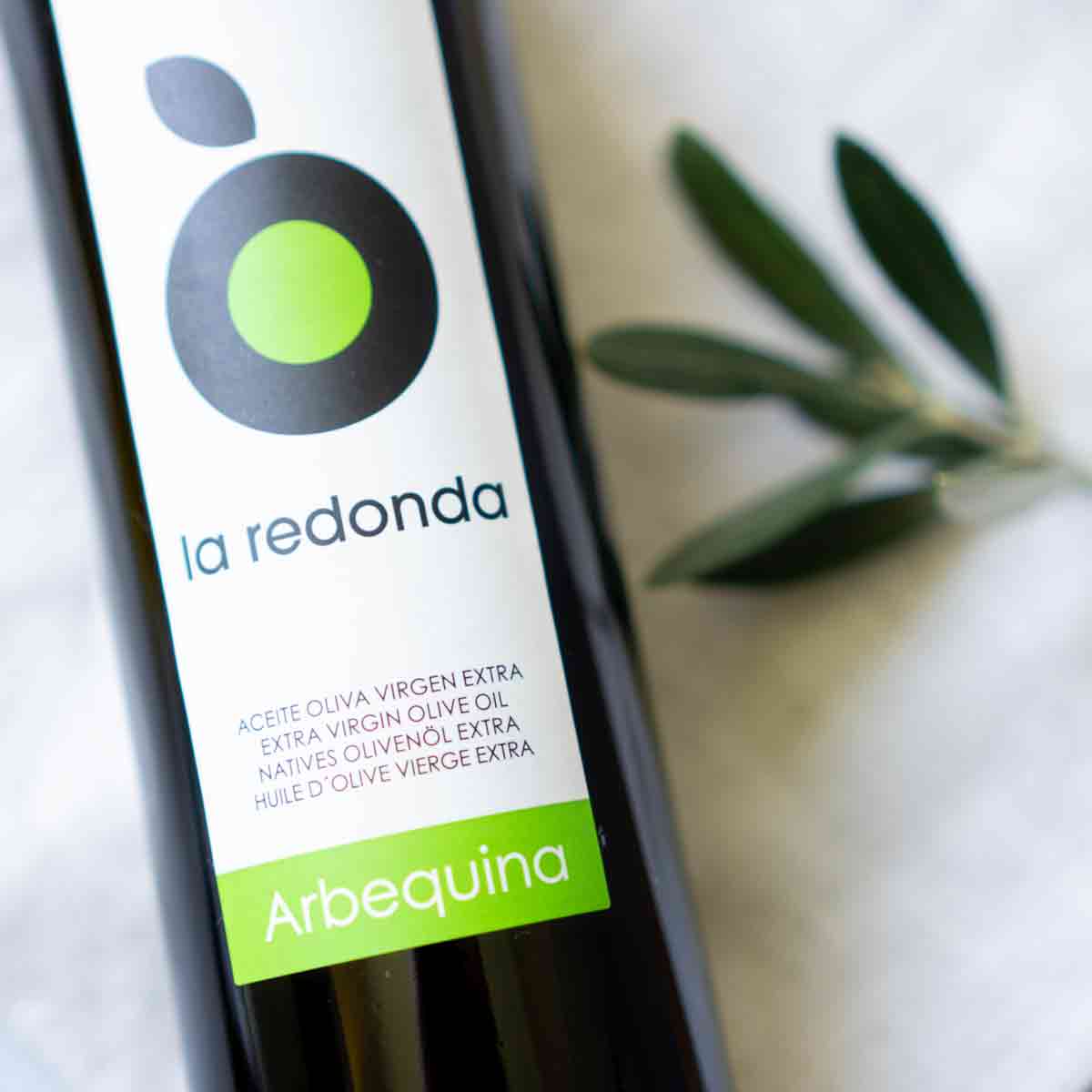 La Redonda Olivenölflasche mit Olivenzweig daneben.