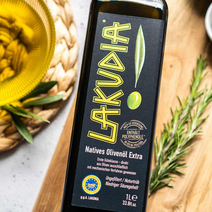 Lakudia Olivenölflasche auf Holztisch mit Rosmarin.