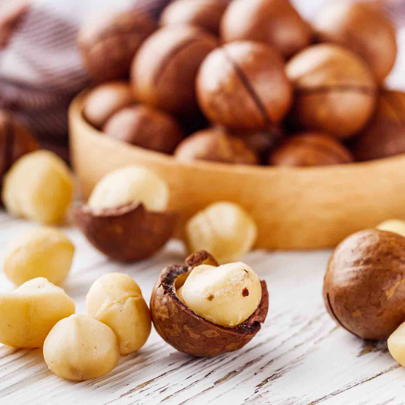 Macadamianüsse in Schale und ohne Schale auf Tisch.