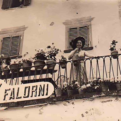 Altes schwarz-weiß Foto mit einer Frau auf dem Balkon an dem das Schild der Macelleria Falorni hängt