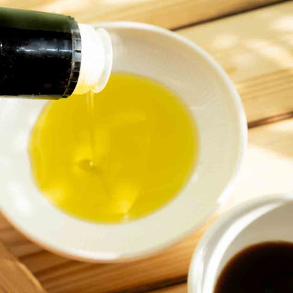 Olivenöl und Essig in weißen Schalen auf Holztisch.