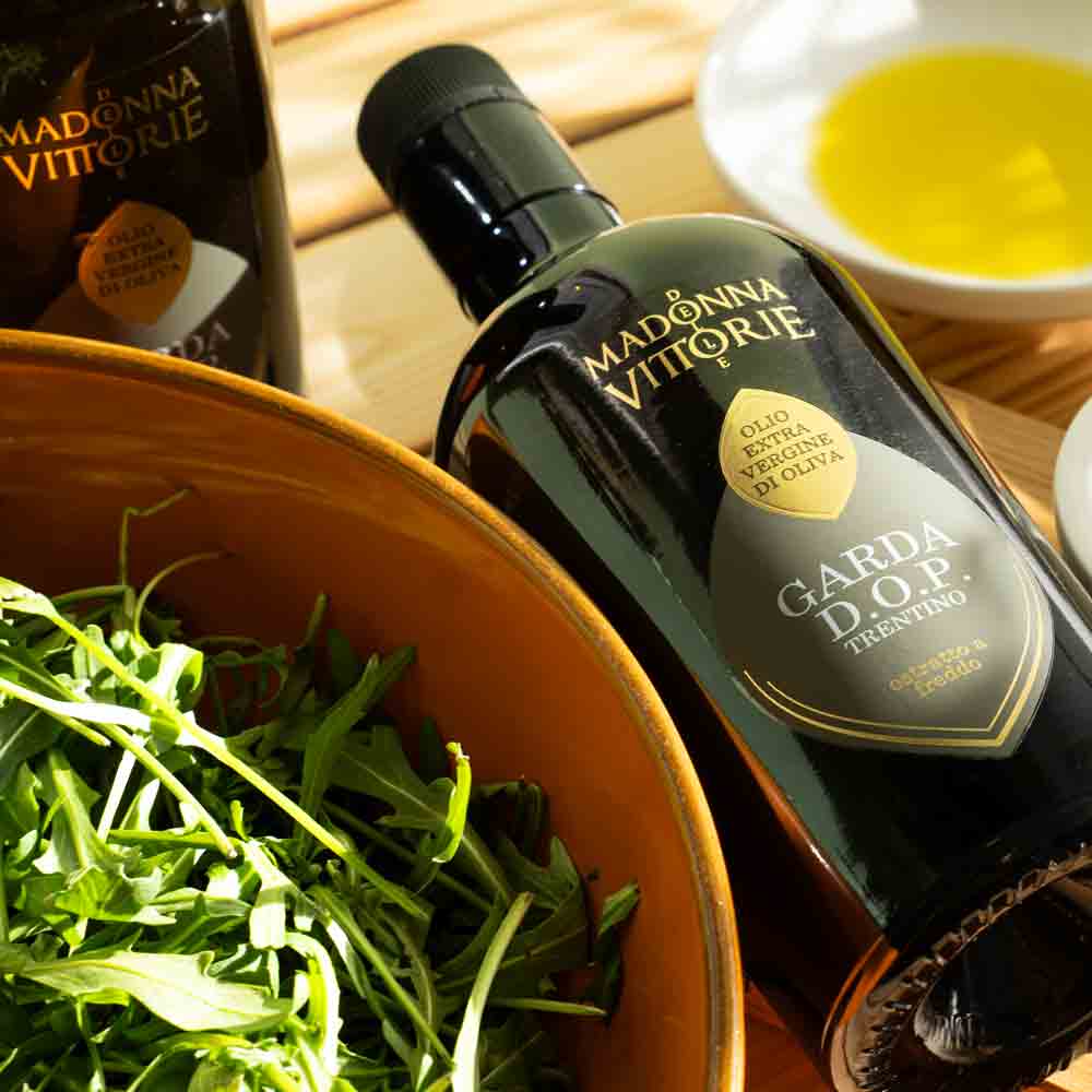 Olivenölflasche Madonna Vittorie neben Salat und Schale.