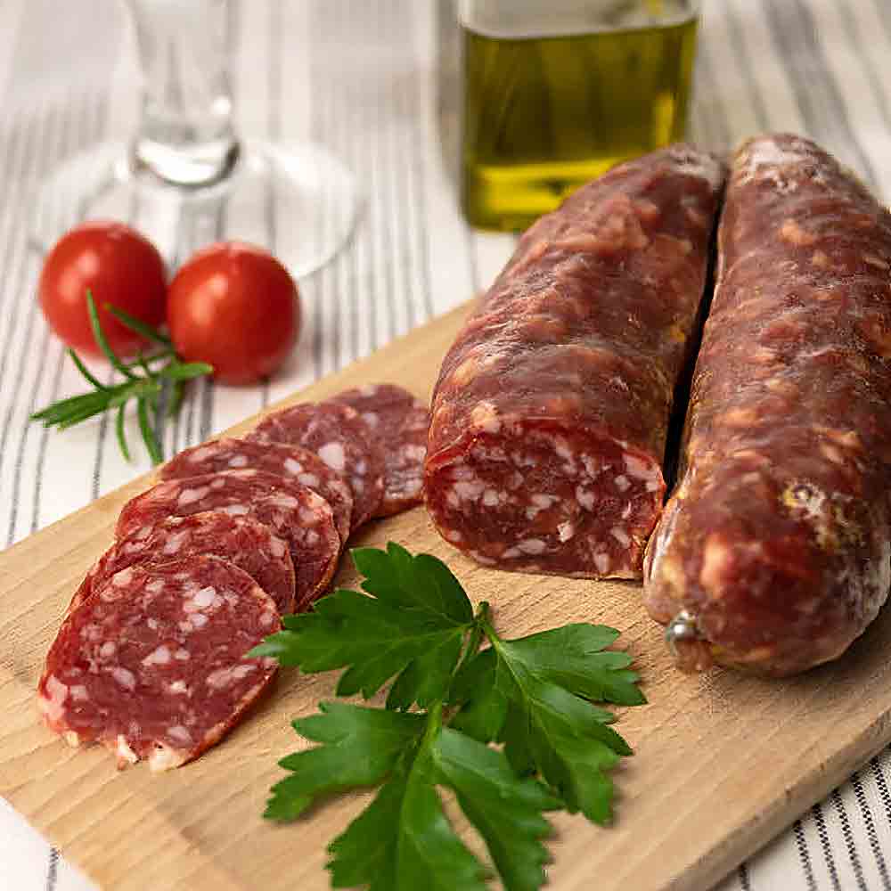 Salsiccia, Olivenöl, Tomaten, Petersilie auf Holzbrett arrangiert.