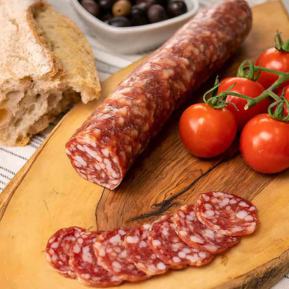 Wurst, Tomaten, Brot und Oliven auf Holzbrett arrangiert.