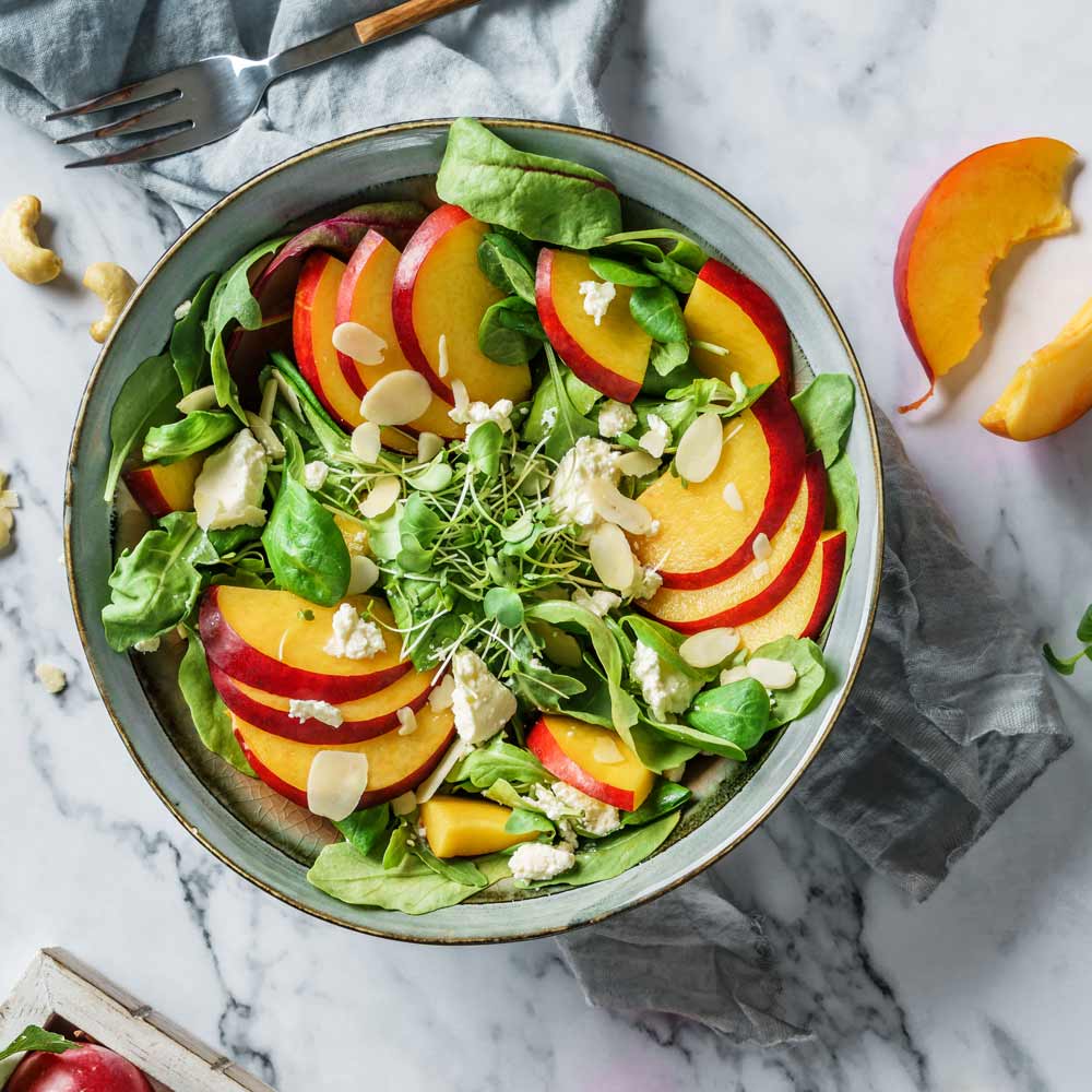 Salat mit Pfirsichen, Mandeln, Käse und frischen Kräutern.