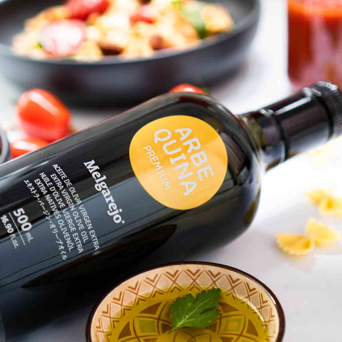 Olivenölflasche Melgarejo Arbequina neben Schale und Pasta.