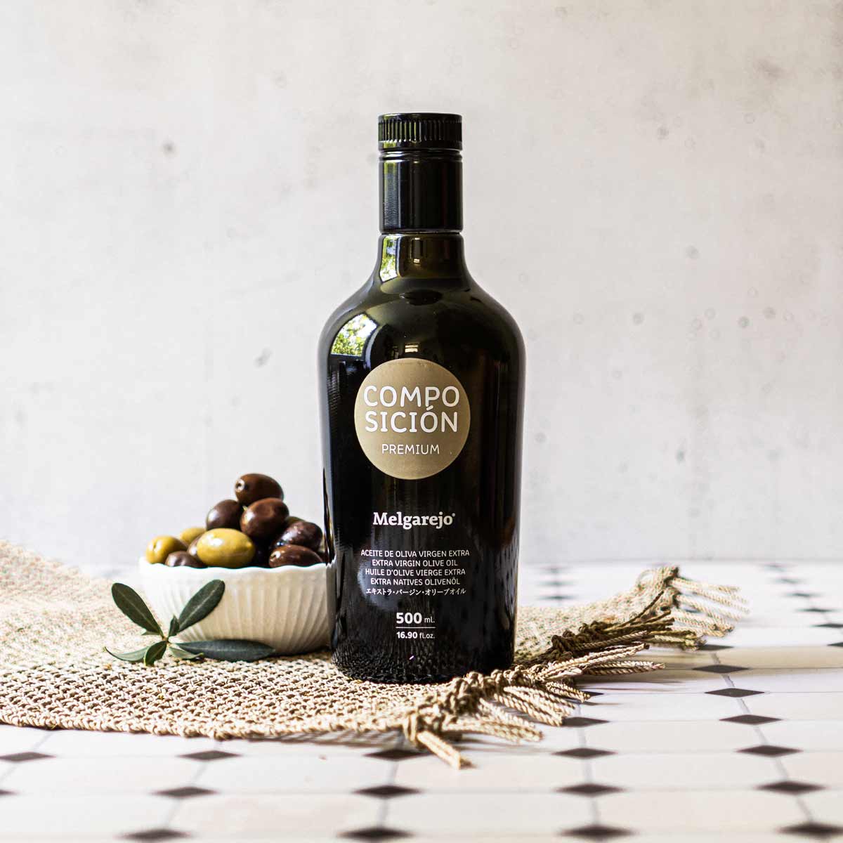 Olivenölflasche Melgarejo, Schale mit Oliven, rustikales Tuch.