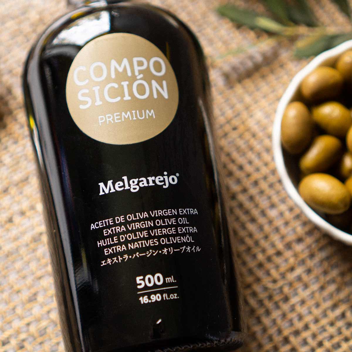 Melgarejo Olivenölflasche neben Schale mit Oliven.