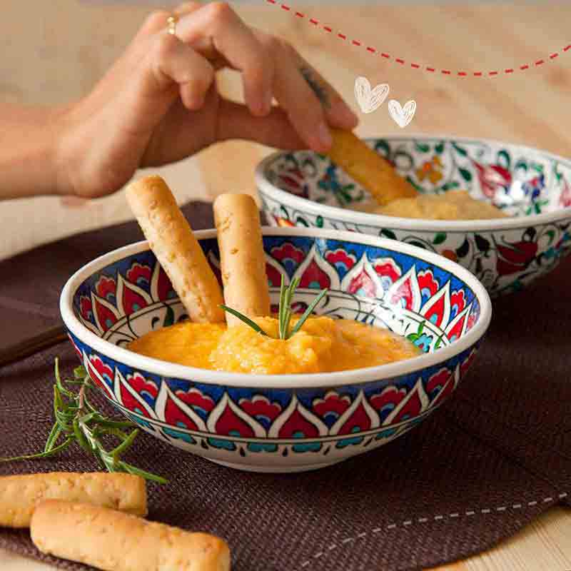 Person dippt Grissini in Schale mit Dip.