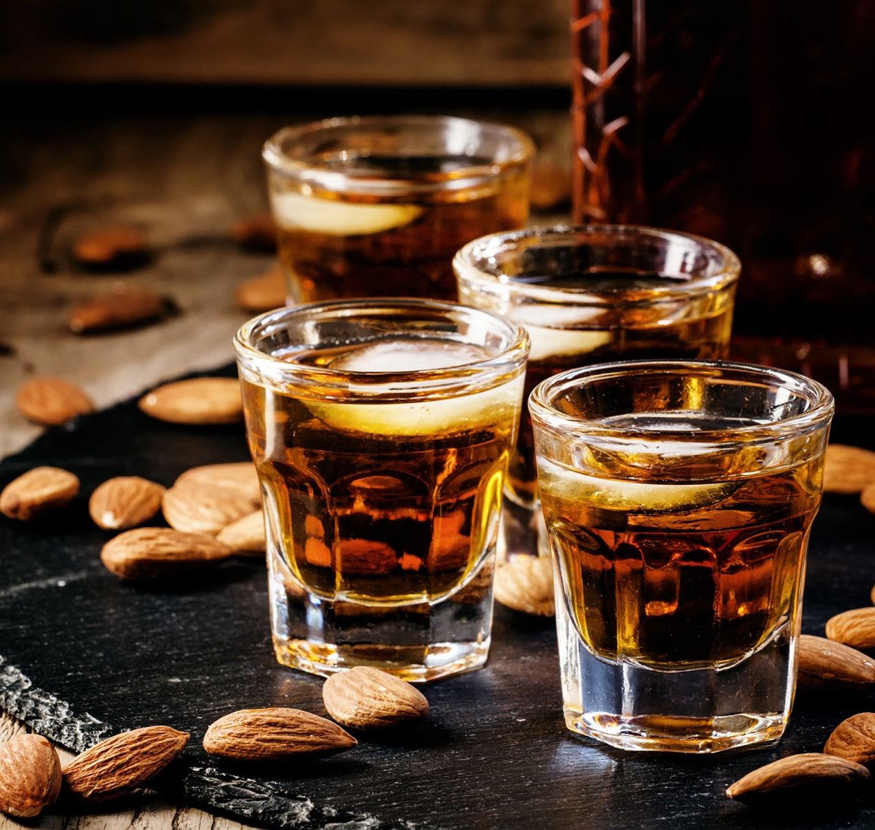 Gläser mit Mussini Balsam Amaretto und Mandeln auf Schiefer.