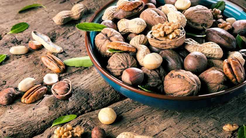 Schale mit verschiedenen Nüssen auf Holztisch.