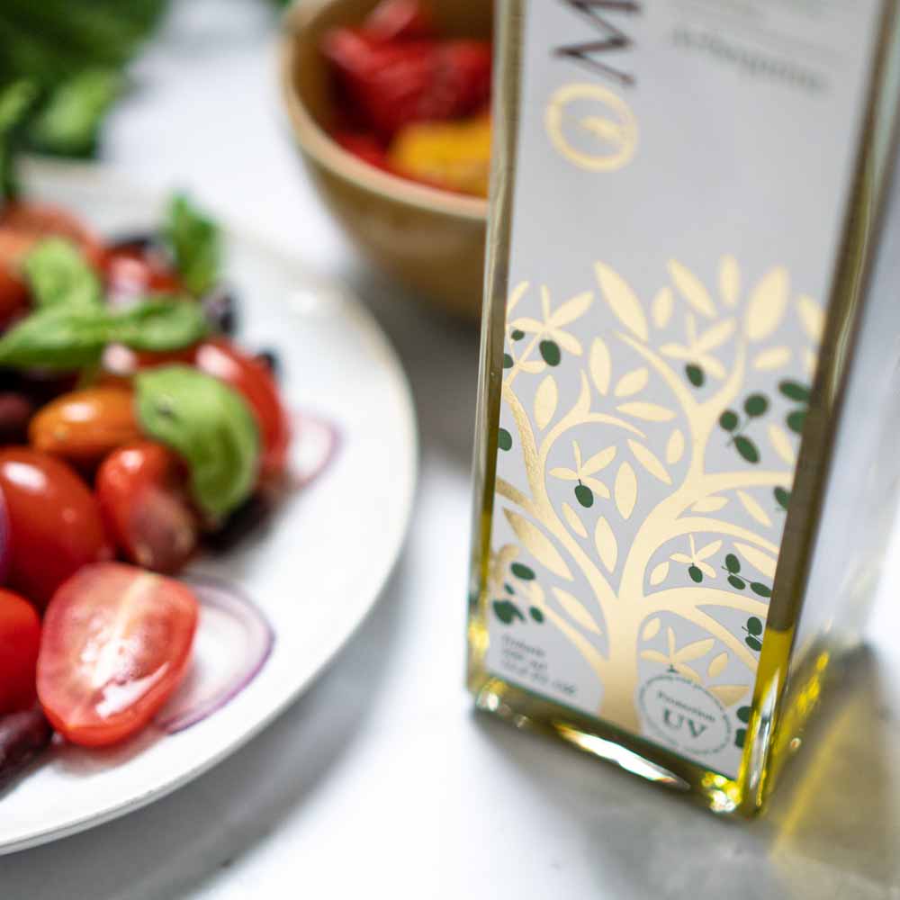 O-Med Arbequina Olivenöl neben Salat und Gemüse.