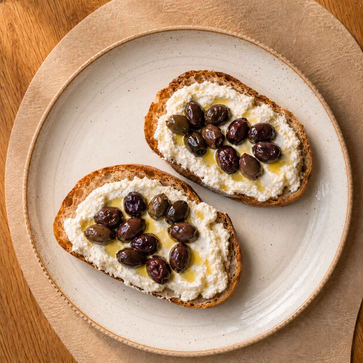Fertige Oliven-Confit mit Ricottacreme auf Weißbrot
