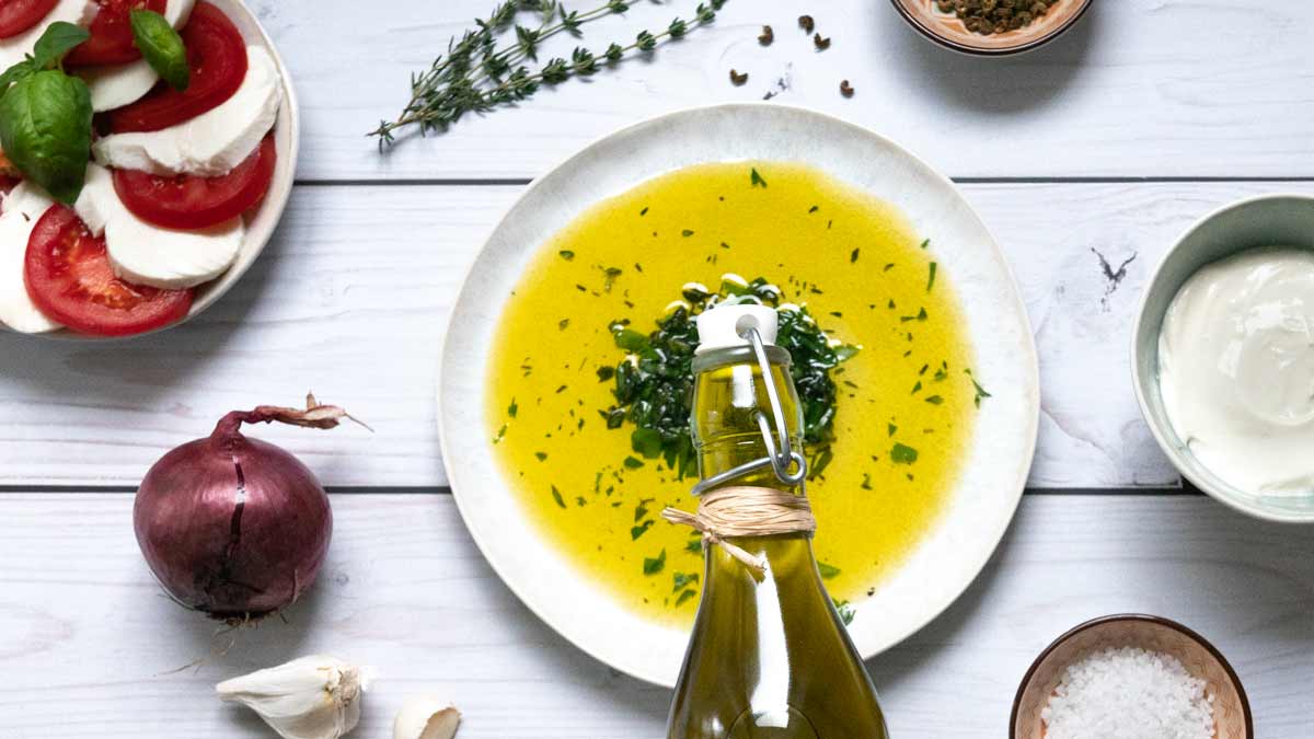 Olivenölflasche, Teller mit Öl, Kräuter, Gemüse, Gewürze, Zwiebel.