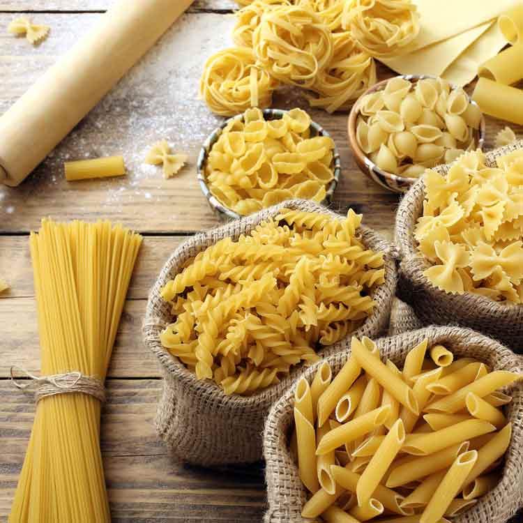 Verschiedene Nudelsorten auf einem Holztisch arrangiert.