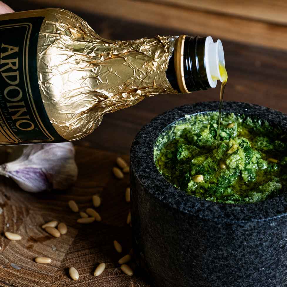 Olivenöl wird zu einem selbst gemachtem Pesto Genovese in den Mörser hinzugefügt