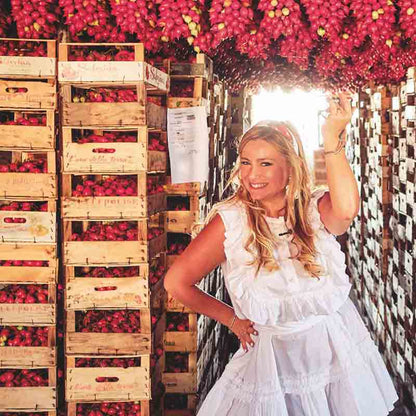 Frau mit Tomaten in Holzkisten.