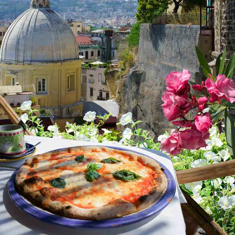 Pizza auf Esstisch mit Ausblick auf Neapel
