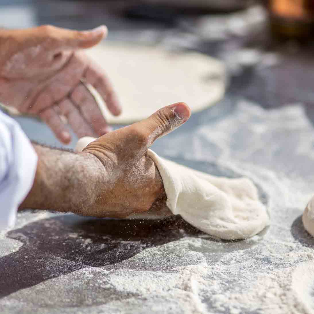 Pizzabäcker knetet Pizzateig