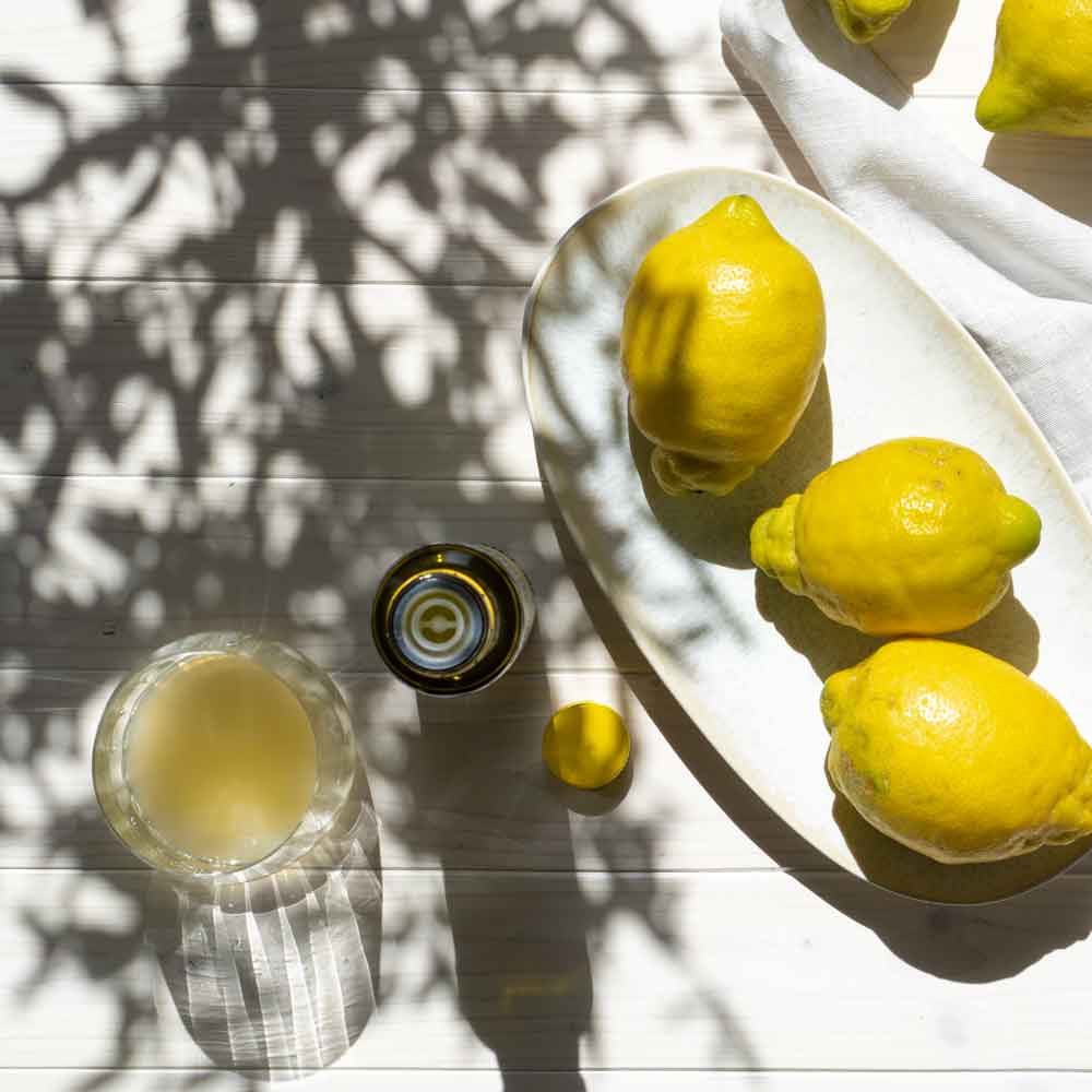 Zitronen und Zitronensaftflasche auf weißem Tisch.