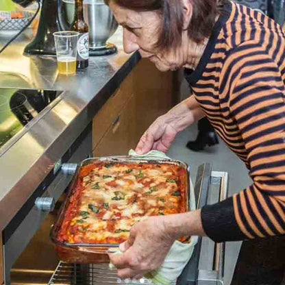 Eine italienische Mama schiebt eine selbstgemachte Pizza in den Ofen.