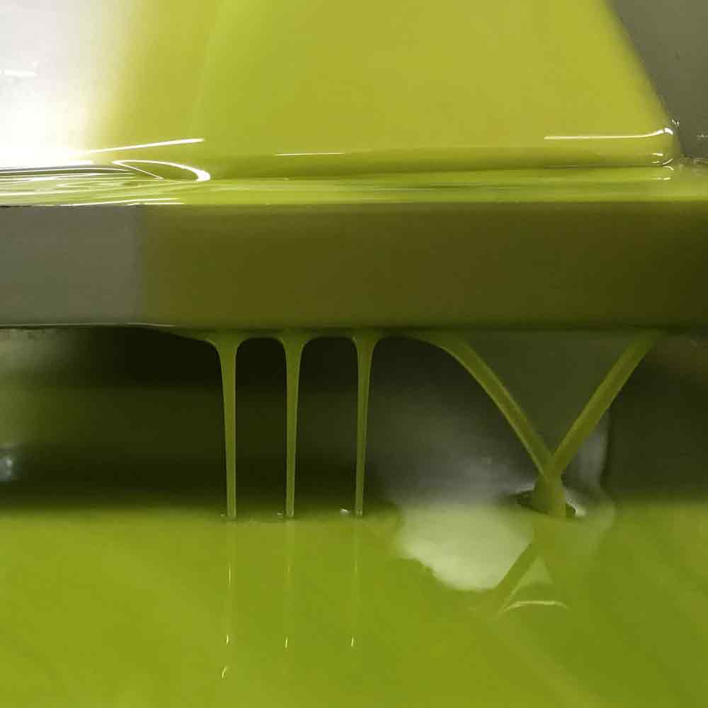 Olivenöl fließt aus einer Presse in einem Produktionsprozess.